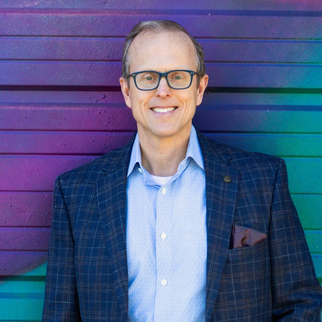 Headshot of a man in front of a gradient wall